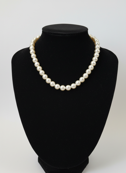 Pearl necklace on a black bust against a white background