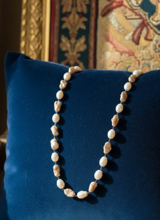 Pearl necklace on a blue pillow with a decorative background